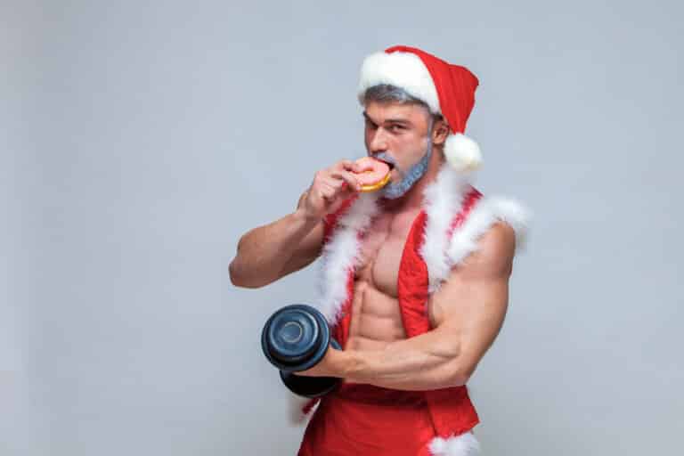 7 Profi-Tipps, um deine hart erarbeitete Figur über die Feiertage zu behalten – Ernährung und Training in Balance Muskulöser Weihnachtsmann kümmert sich um Ernährung während den Feiertagen