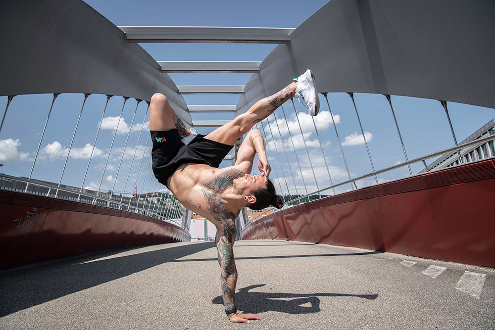 Breakdancer tanzt auf einer Brücke.
