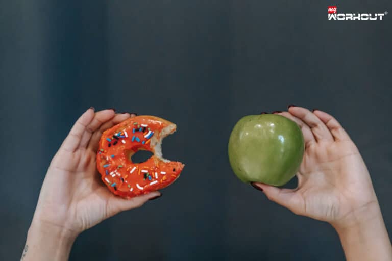 Die «Reverse» Diät Linke Hand hält einen Donut und die rechte Hand hält einen Apfel