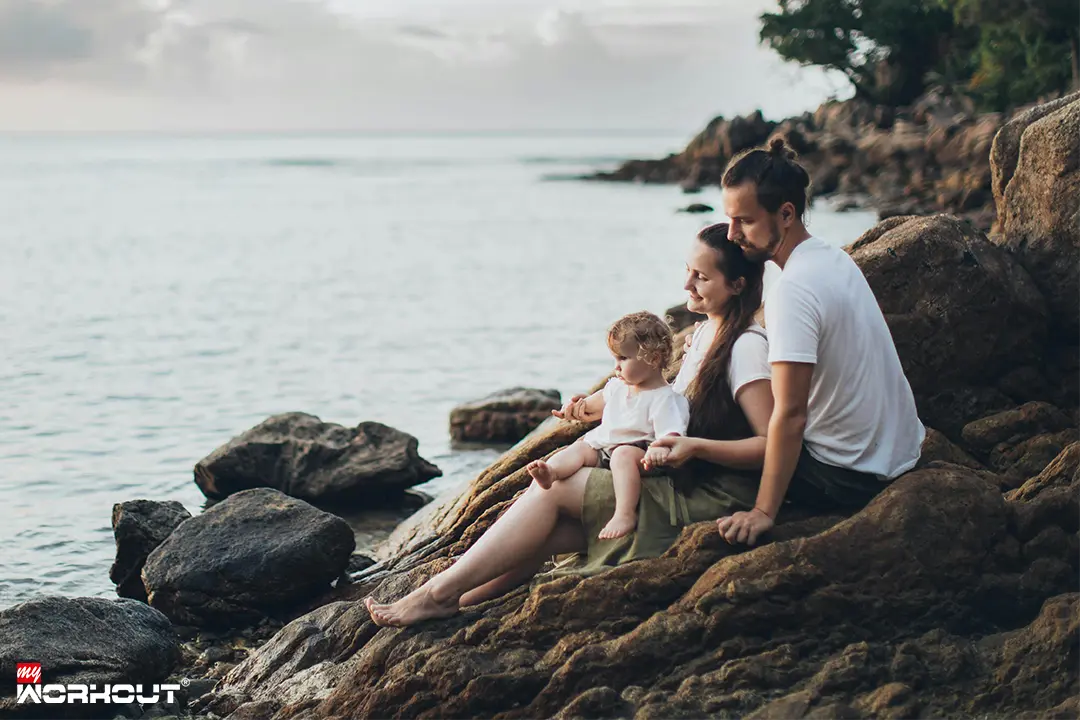 Familie sitzt auf Steinen am Wasser 