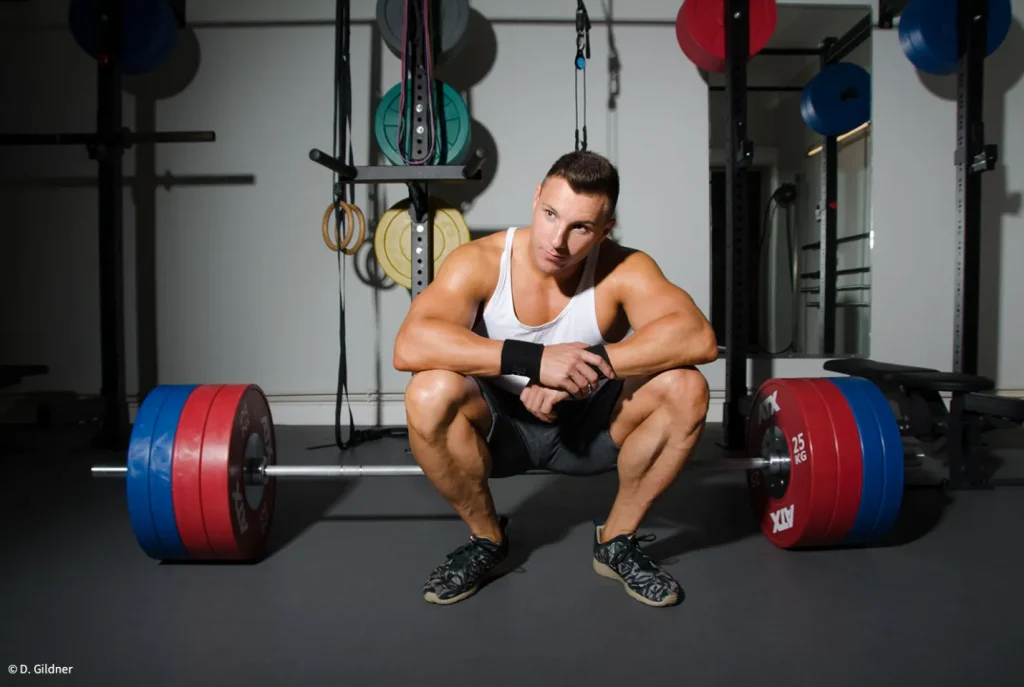 Bodybuilder Daniel Gildner sitzt auf dem Langhantel